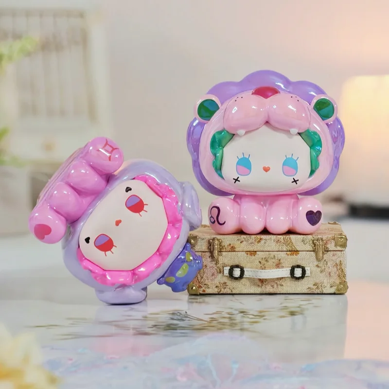 A pink and purple collectible figurine of a lion face with green accents sitting on a wooden box.