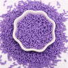 Purple polymer clay slice sprinkles scattered on a white surface, with a central mound.