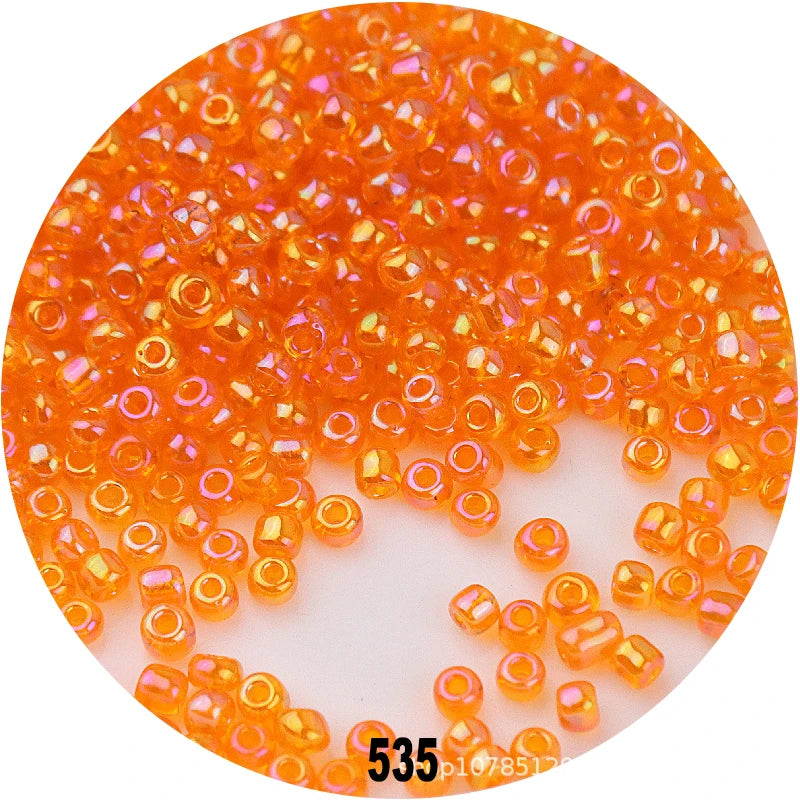 A circular image showing a pile of small, round, colorful glass seed beads in various shades of orange and yellow.