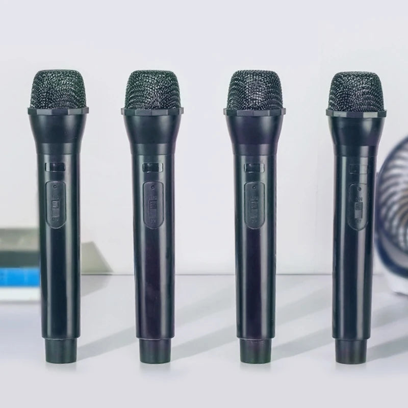 Four black realistic toy microphone props lined up on a white surface.