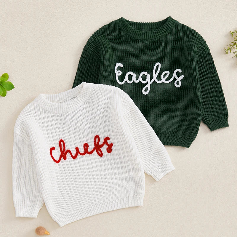 A white knit sweater with red embroidery spelling out chefs and a dark green sweater with white embroidery spelling out eagle