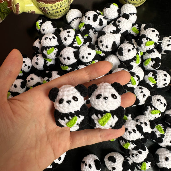 A hand holds a cluster of black and white crochet kitten keyrings with panda charms.