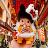 A cute Monchhichi plush keychain with black fur, white ears, and a yellow outfit being held against a traditional Chinese arc