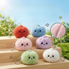 A collection of adorable squishy dumpling keychain plush toys in various pastel colors resting on a wooden tray.