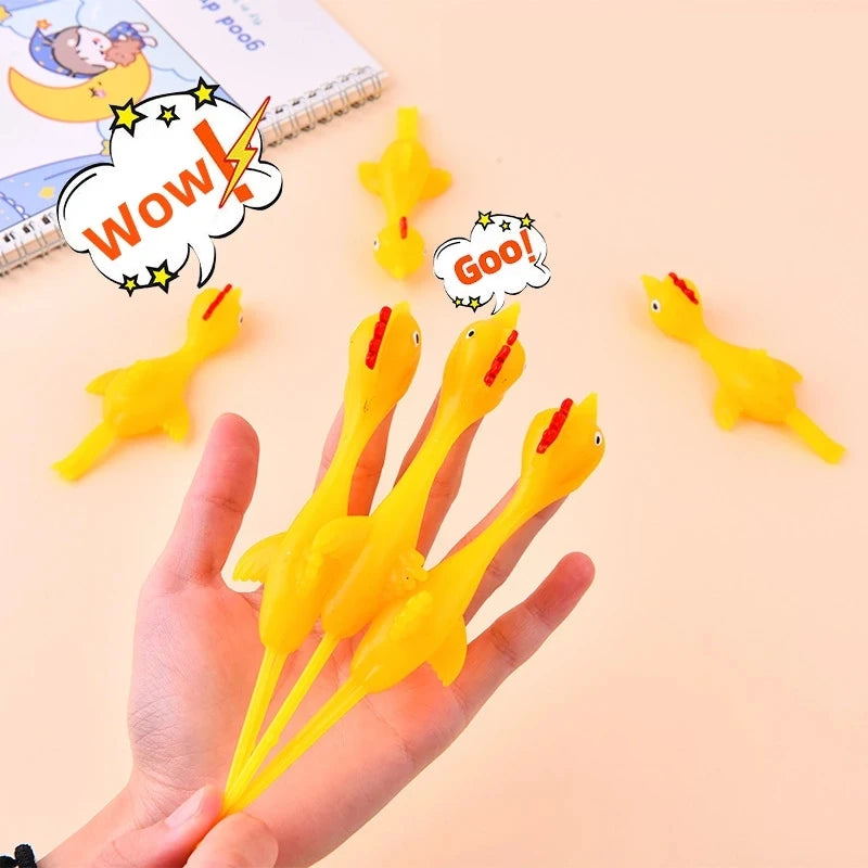 A hand holds several yellow catapult chicken flying toys with speech bubbles showing wow and goo.