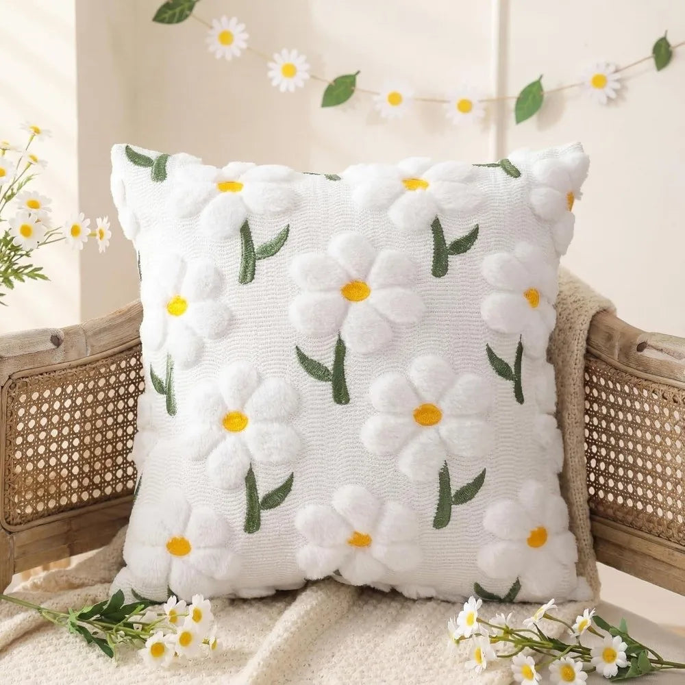 White faux fur pillow covers with embroidered yellow and green daisy designs resting on a woven chair.