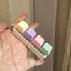 A hand holds a fidget keychain stress reliever with five colorful, square keys.