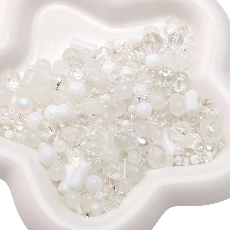 A pile of multicolor glass beads in various sizes and opacities is displayed in a white mold.