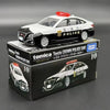 A black and white Toyota Crown police car model in a box, featuring a red light bar.