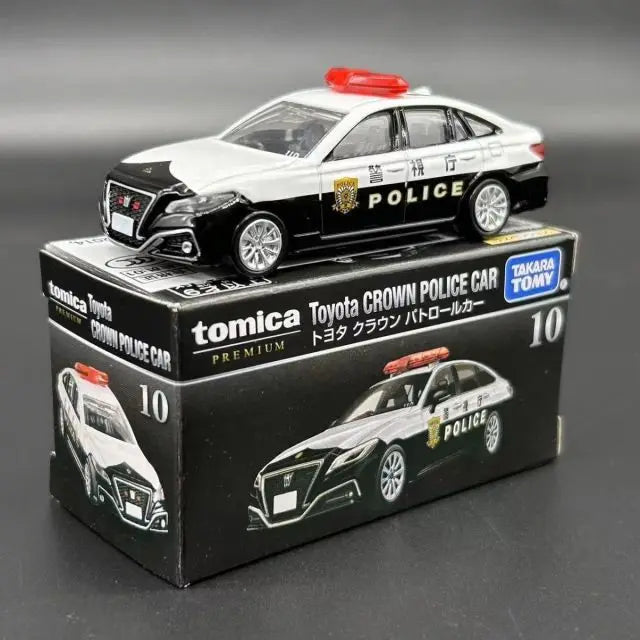 A black and white Toyota Crown police car model in a box, featuring a red light bar.