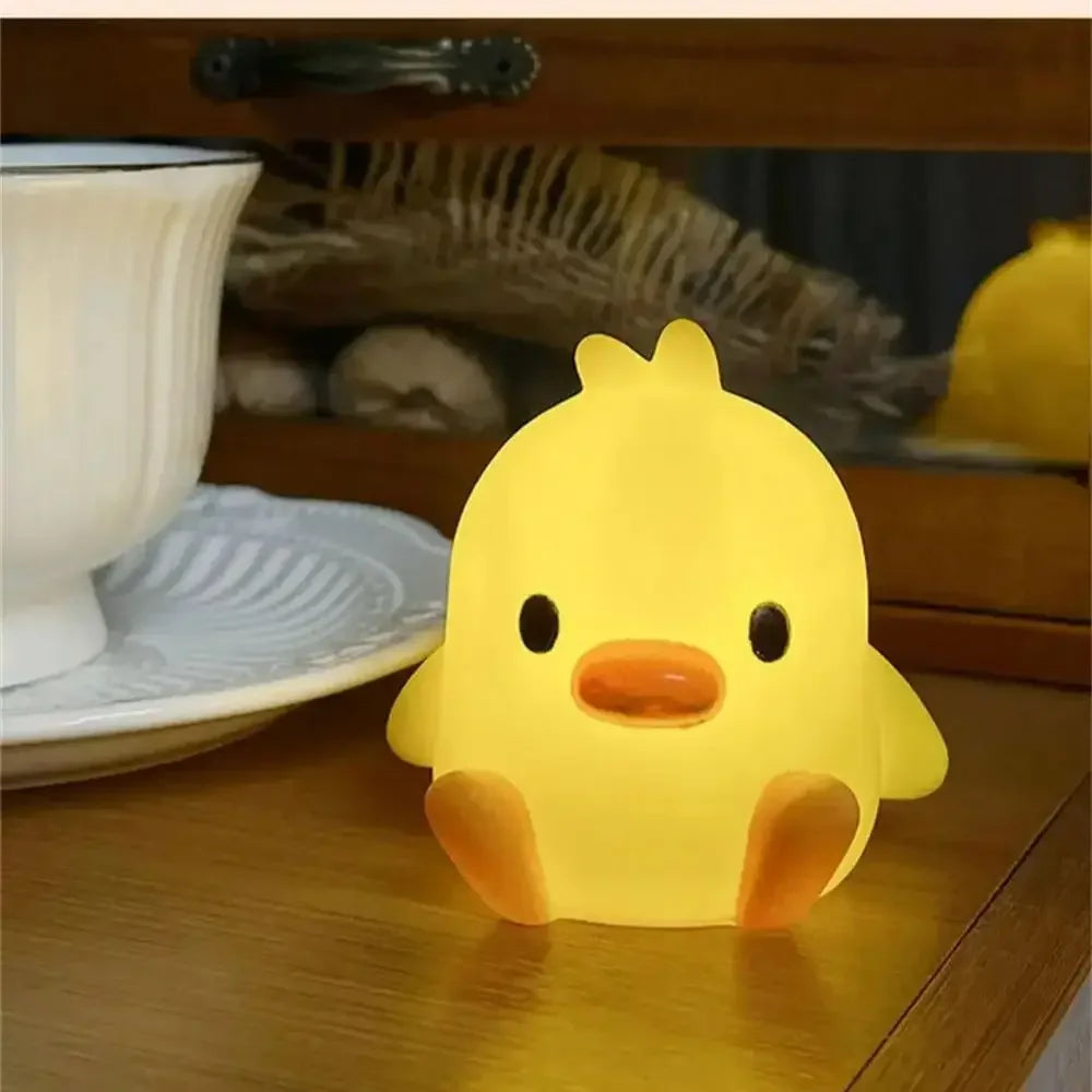 A bright yellow cartoon duck night light sitting on a wooden surface next to a white bowl.