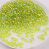 A pile of bright lime green glass rice beads for DIY jewelry and crafting.