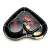 A black love-shaped metal rolling tray holds a glass jar and a rectangular metal herb grinder.