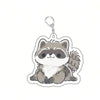 A cute raccoon charm with gray and white fur attached to a silver keyring.
