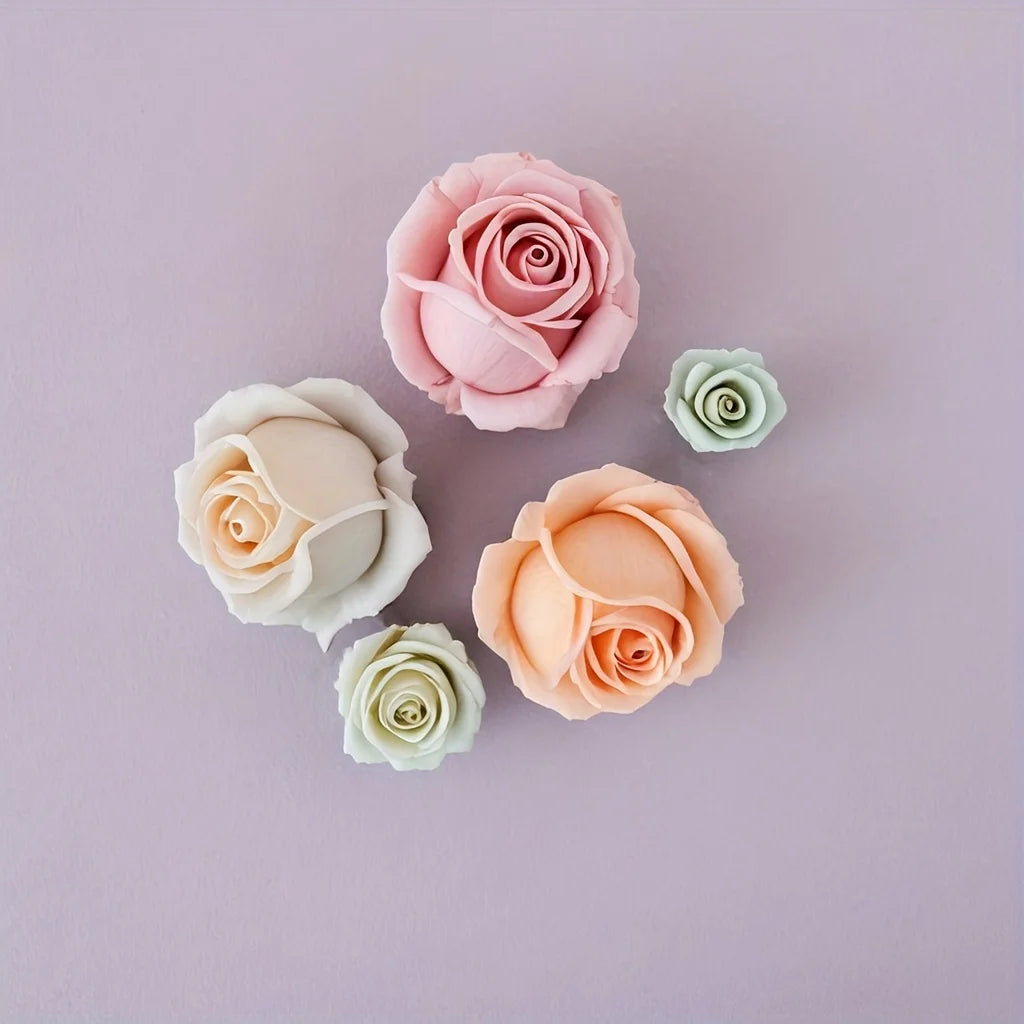 A collection of five pink and peach silicone rose molds in various shades and sizes on a light purple background.