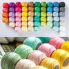 A collection of colorful 100% cotton crochet thread in various shades and textures arranged in rows.