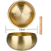 A brass singing bowl with a wooden mallet and a separate bowl for sound healing.