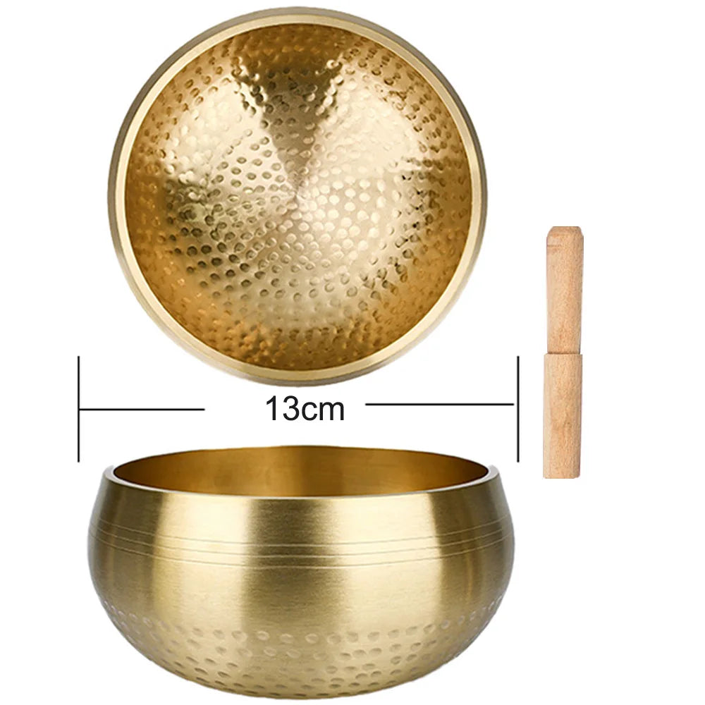 A brass singing bowl with a wooden mallet and a separate bowl for sound healing.
