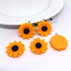Several bright orange sunflower charms with black centers are displayed on a white background.