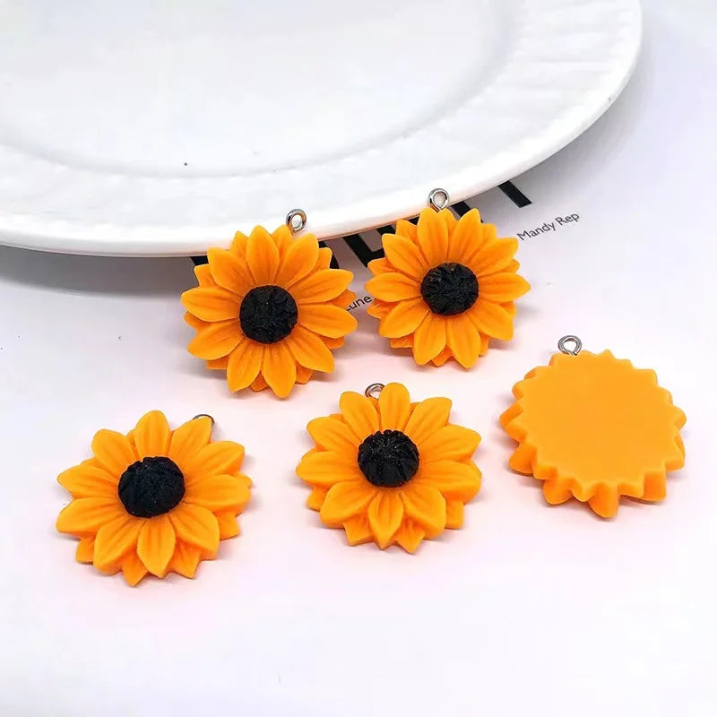 Several bright orange sunflower charms with black centers are displayed on a white background.