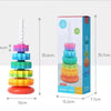 A colorful rainbow spinning stacking tower toy for toddlers shown next to its packaging.