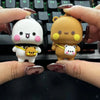 A pair of cute cartoon bear keychains, one white and pink, and one brown, are held above a mechanical keyboard.