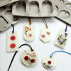 A collection of handmade soap and candle tags made from white silicone, featuring floral designs and various colors.