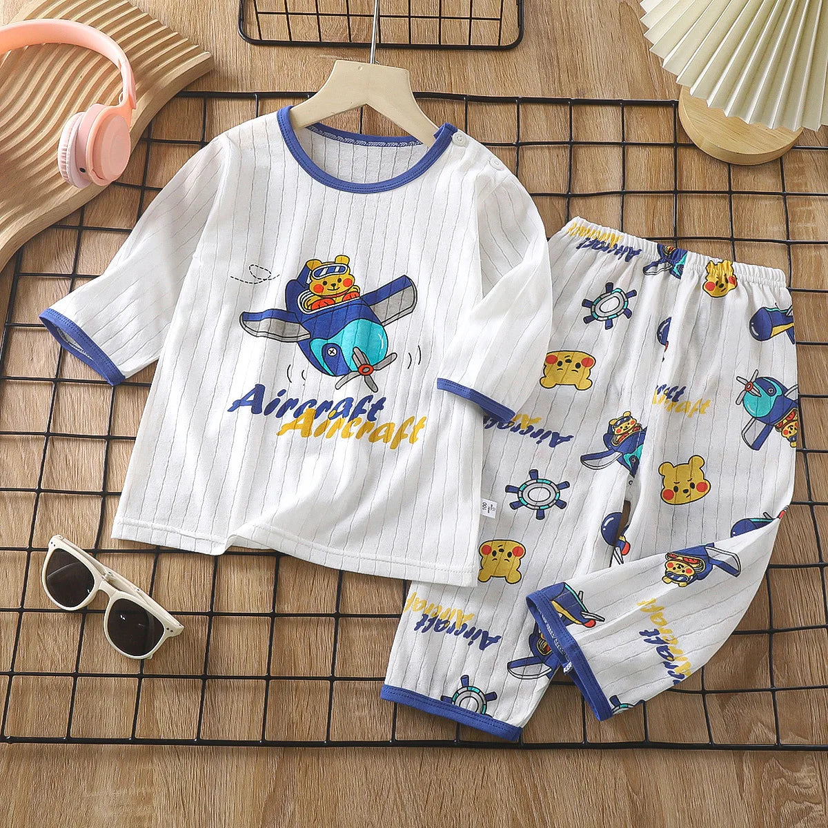 White long sleeve cotton pajama set for kids featuring an aircraft print and various animal motifs