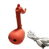 An orange Otamatone mini electronic musical instrument toy with a white cord.