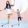 A young girl is balancing on a glowing skip ball while holding a purple skipping rope.