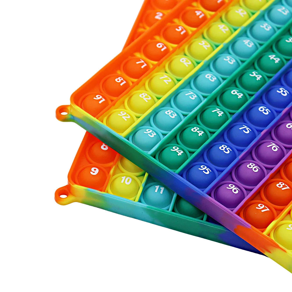 A close-up view of a colorful multiplication pop-it math fidget toy with numbered plastic balls in various bright colors.