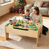 A young boy and woman play with a wooden train set on a table, featuring an activity top and storage drawer.