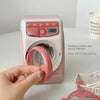 A hand is opening a pink kids pretend play kitchen appliance with a door to access the roller.