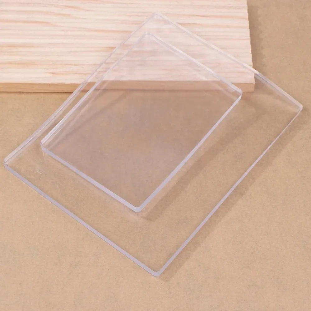 Clear silicone gel printing plates stacked on a light wooden surface for mixed media art