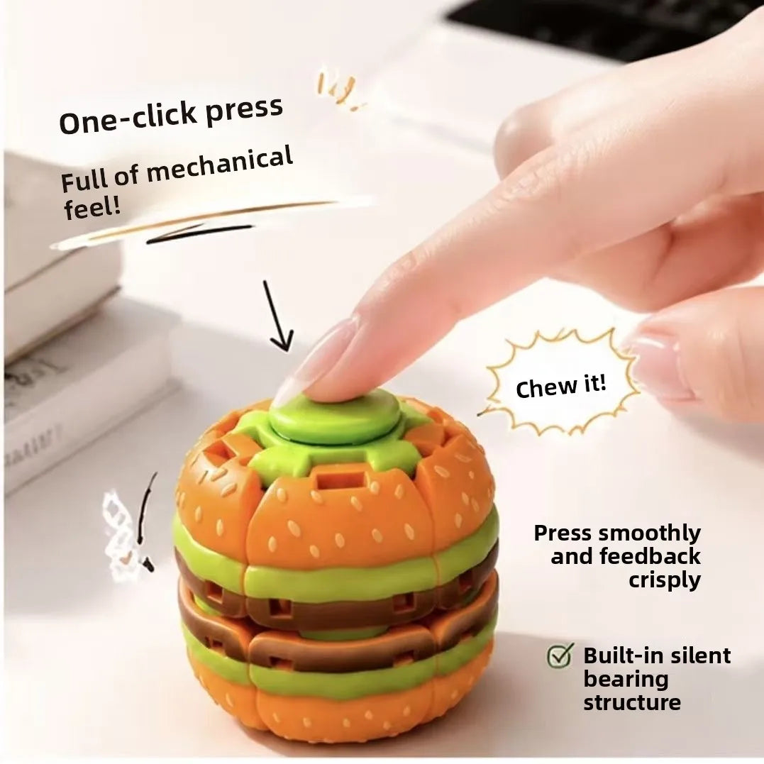 An orange and green burger-shaped stress relief toy is being pressed by a finger, demonstrating its mechanical feel.