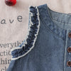 A close-up of a denim sleeveless dress for a toddler girl featuring delicate lace trim on the neckline.