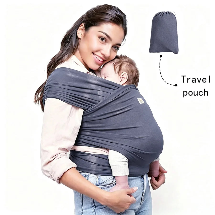 A woman wearing a grey knitted fabric multi-functional baby carrier with a travel pouch, holding a baby.