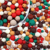 A collection of matte acrylic beads in various colors including red, orange, brown, white, and green.
