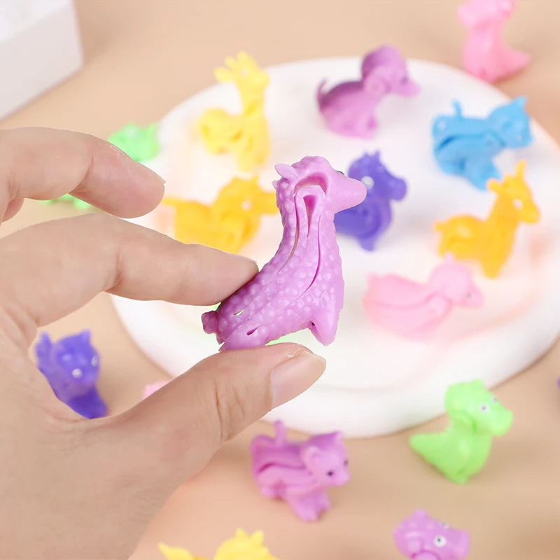A hand is holding a purple animal sensory stress bracelet among various colorful plastic dinosaur and animal figures.
