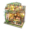 A detailed DIY miniature dollhouse kit featuring furniture, plants, and warm lighting.