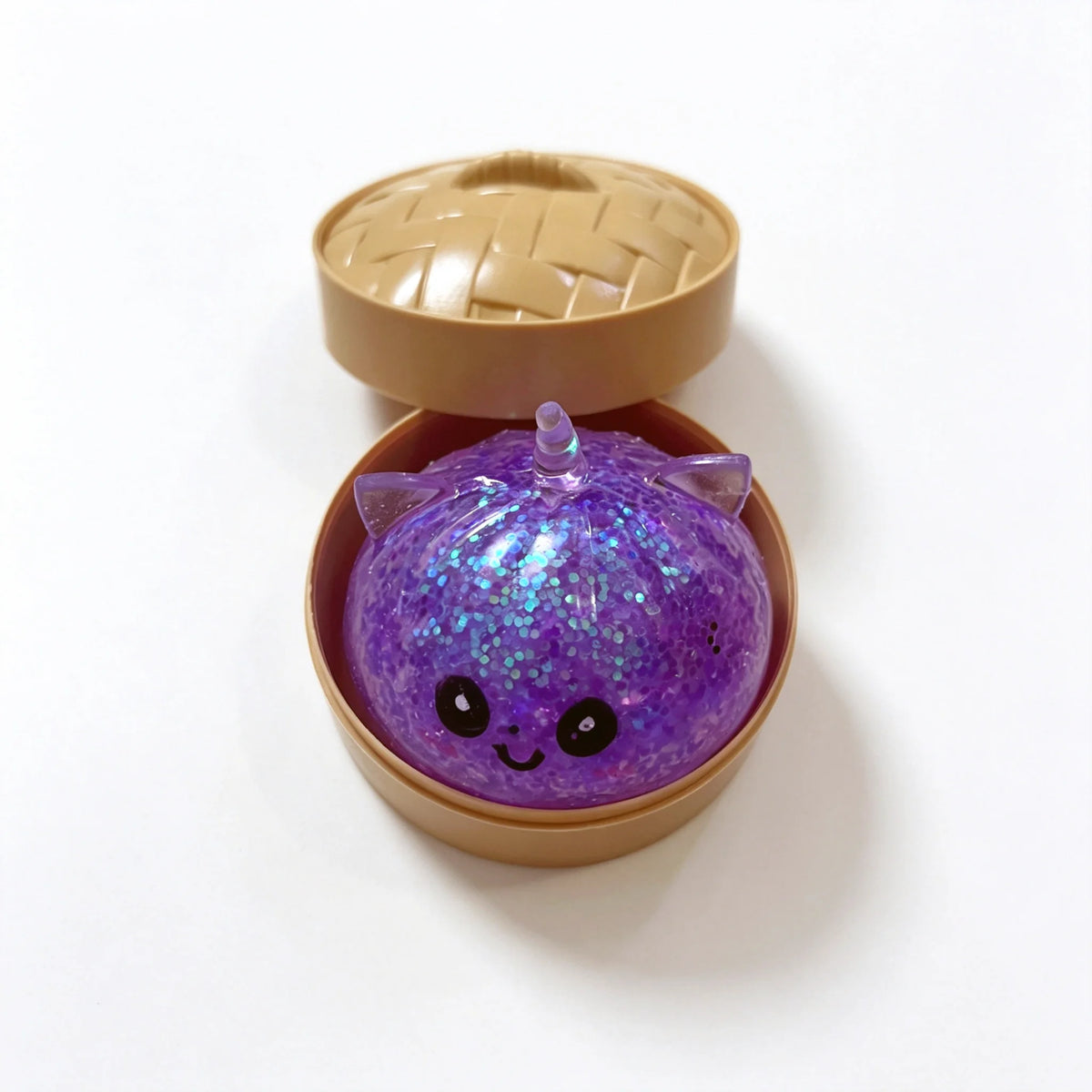 A purple unicorn dumpling squishy stress ball is shown inside its bamboo steamer box.