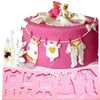 Pink silicone cake molds set featuring baby items like a stroller, bottle, pacifier, and clothing.