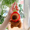 A hand holds an adorable brown capybara plush keychain charm with a green leaf detail.