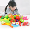 A child is using a colorful pretend play kitchen set with plastic fruits and vegetables for imaginative play.