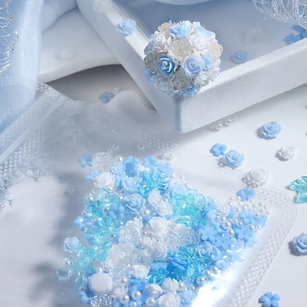 Blue and white camellia resin flower fillers in a shaker, scattered on a white surface.