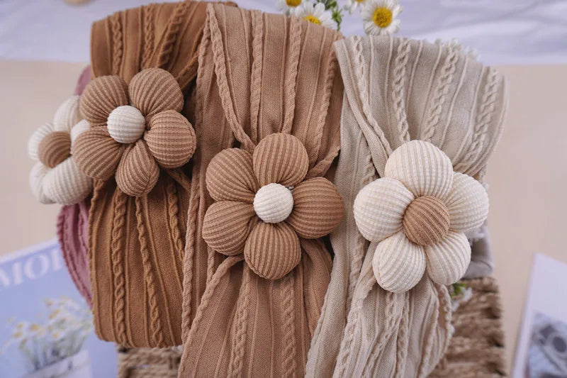 Three knitted floral elastic baby headbands in beige and tan colors