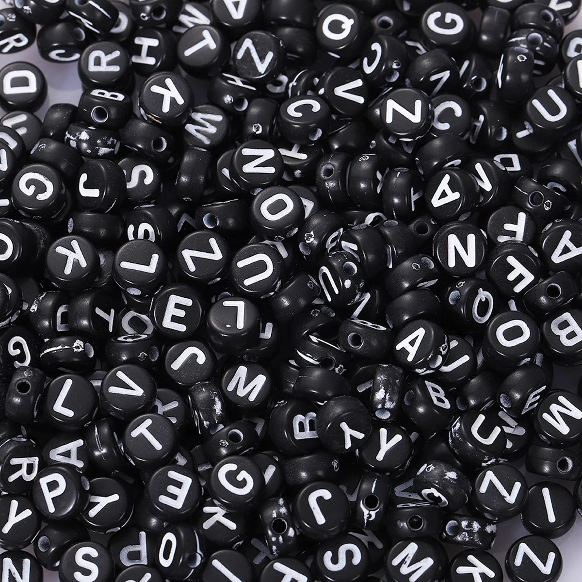 A close-up view of a pile of black acrylic alphabet beads for jewelry making