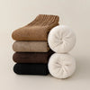 A stack of women's fleece-lined slouch socks in various shades of brown, beige, and black.
