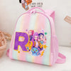 A pink backpack featuring a large purple letter R and anime characters on a rainbow gradient background.