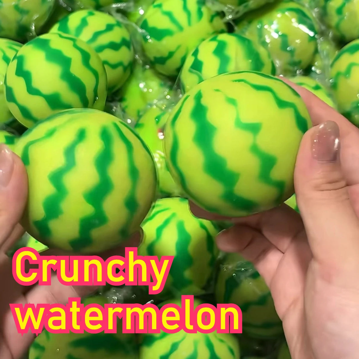 A hand holds a bright green watermelon squishy stress ball with a striped texture.